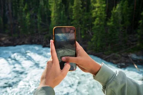 Capturing scenic river view with smartphone, preserving natural beauty. Stock Photos