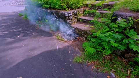 Capturing of smoke coming out of bonfire beside stone steps near a road in Stock Footage 313249710
