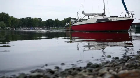Caputh, Germany - September 10, 2025: Red sailboat anchored on the Havel River Stock Footage 317117689