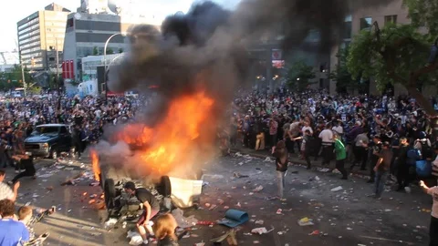 Car ablaze in middle of rioting crowd after bad ending to local hockey game Stock Footage 127199479