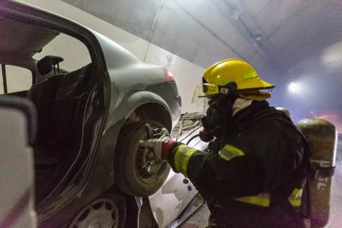 Car accident scene inside a tunnel, firefighters rescuing people from cars Foto stock