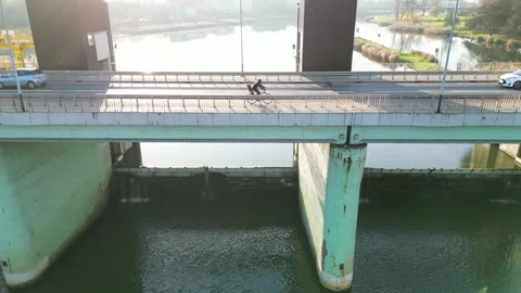 Car and cyclist navigate a bridge dam scene, showcasing dynamic traffic Video stock 321161964