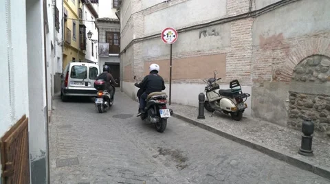 Car and motorcycles squeezing through narrow cobblestone alley. 库存影片 55706820