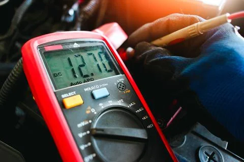 Car battery voltage testing with a digital multimeter by auto technician Stock Photos
