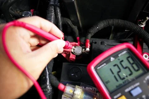 Car battery voltage testing with a digital multimeter by auto technician Stock Photos
