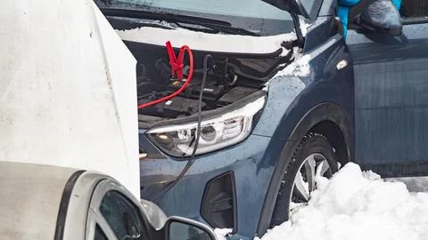 Car is being jump started in snowy weather in winter season during daylight.. Stock Photos