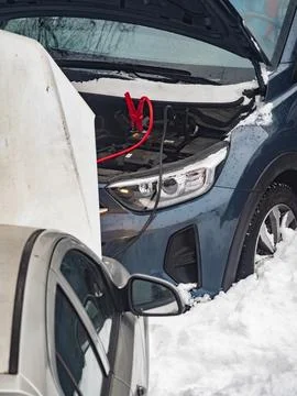 Car is being jump started in snowy weather in winter season during daylight.. Stock Photos