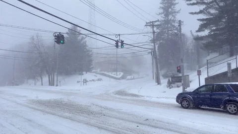 Car With Blinking Hazard Lights Drives Through Intersection During Snowstorm Stock Footage 85282502