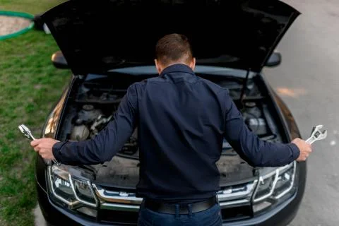 Car breakdown concept. The car will not start. The young man is trying to fix Stock Photos