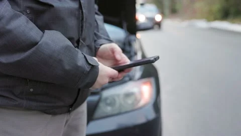 Car broken down by roadside with hazard lights and hood open, man on cellphone Stock Footage 230175589