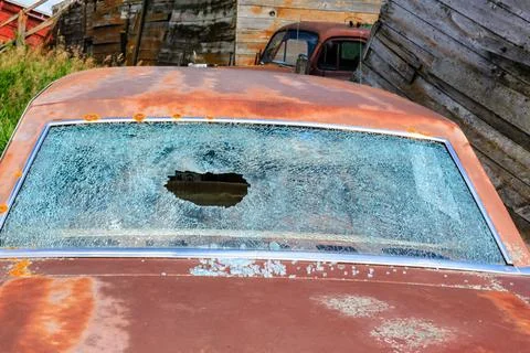 A car with a broken windshield sits in a junkyard Stock Photos