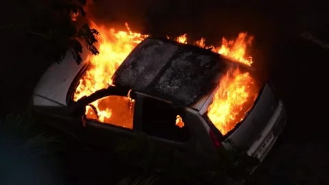 Car burning in fire explosion accident during street riot attack at night Stock Footage 138647339