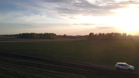 Car casting long shadow drives past accurate green fields 库存影片 112386914