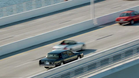 Car chase as black car weaves through traffic over Florida bridge Stock Footage