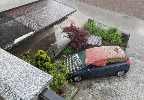 Car covered in blankets during strong hail storm. Car protection against hail Stock Photos