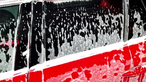 Car covered in soap foam during wash - close up cleaning process detail 库存影片 332761408