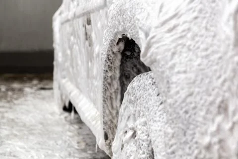 A car covered by soap foam while washing indoors - close-up with selective focus Photos
