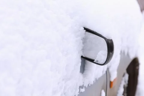 Car is covered in thick snow, side is visible and mirror is visible Stock Photos