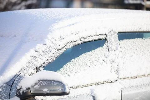 Car covered with a thin layer of fresh white snow. Side view. 写真素材