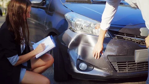 Car crash. Broken car. Insurance agent looking at a damaged vehicle. Woman Stock Footage