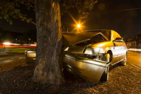 Car crashed on tree trunk during night Stock Photos