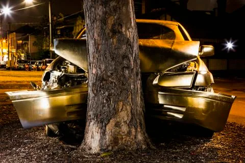 Car crashed on tree trunk at night Stock Photos