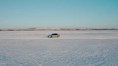 Car Crossing an Open Snowfield Beneath the Winter Sun Vídeo Stock 344955138