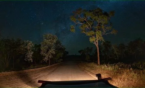 A car is currently driving down a rough dirt road during the night Foto stock
