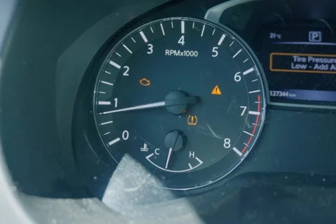 Car dashboard displaying check engine and low tire pressure warning lights Видео 338027843