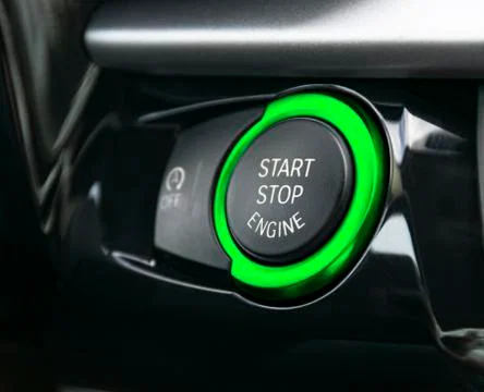 Car dashboard with focus on Green engine start stop button. Modern car interi Stock Photos
