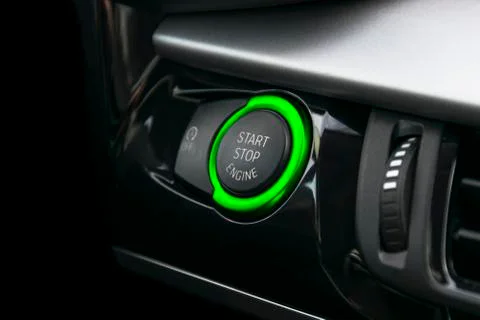 Car dashboard with focus on green engine start stop button. Car interior deta Stock Photos