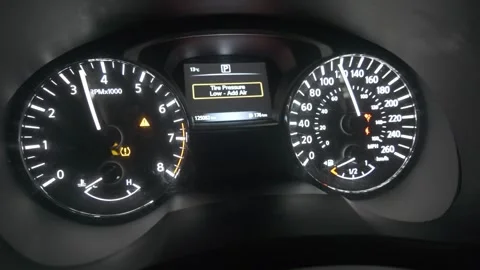 Car dashboard lights up, initializing with a low tire pressure warning icon Stock Footage 322048974
