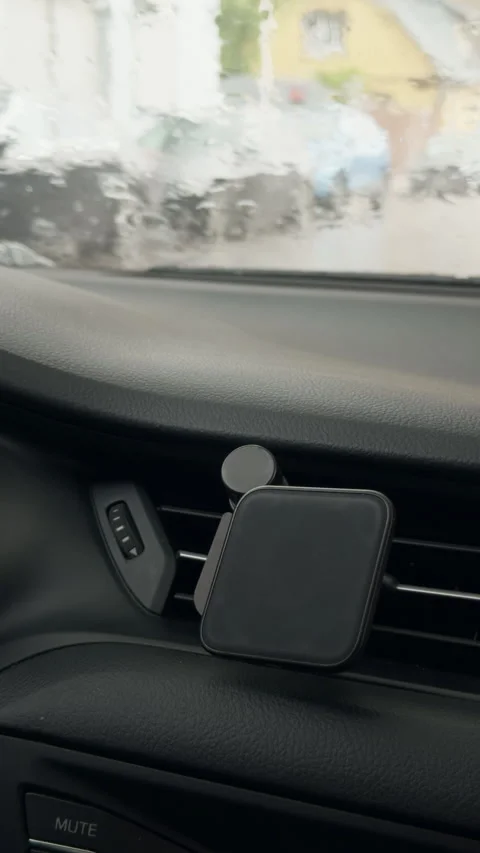 Car dashboard with smartphone holder and rainy blurred windshield view from Stock Footage 345605546