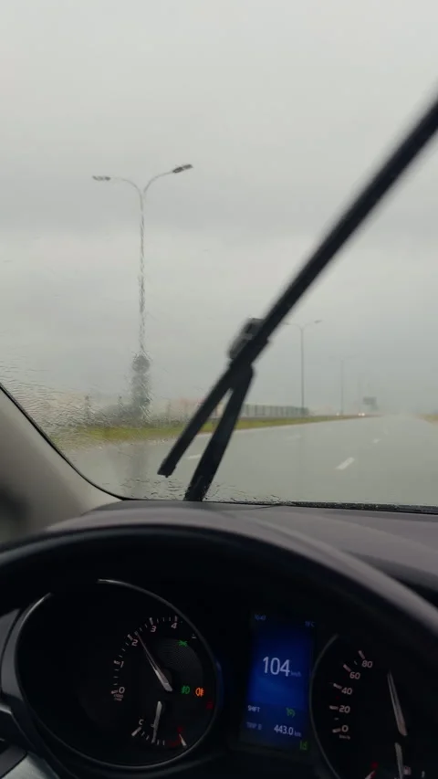 Car dashboard view through rain covered windshield on highway with blurred road Stock Footage 345530351