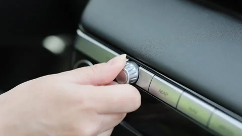 Car dashboard volume knob. Driver's hand adjusts volume control of car radio Stock Footage 272302873