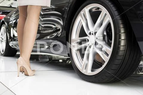 At The Car Dealer, Legs Of A Woman Standing Next To New Car