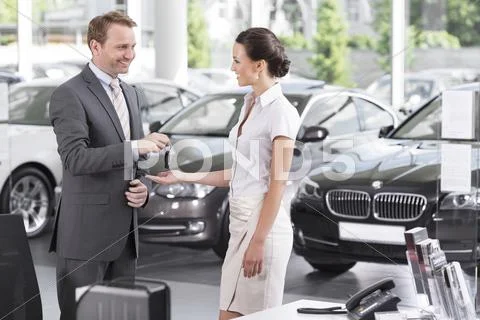 At The Car Dealer, Salesman Handing Over Car Key To Client