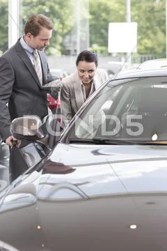 At The Car Dealer, Salesman Showing New Car To Client