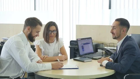 Car Dealer signing a contract to purchase and giving the key to a new car to a Stock Footage