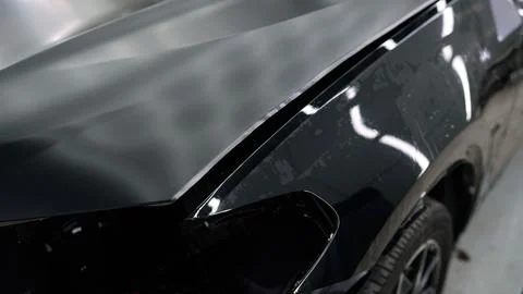 Car detailing process: removing protective film from new car hood Stock Photos