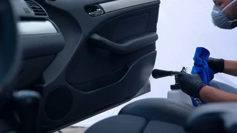 Car detailing. Worker washing of interior by a special cleaners under pressure Stock Footage 115860376