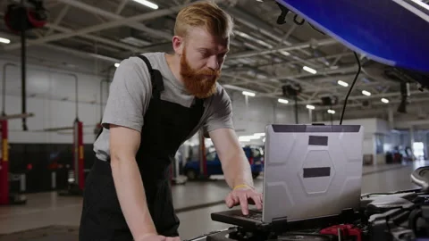 Car diagnostics using a laptop. Man is an auto electrician at a service station Stock Footage 221549145