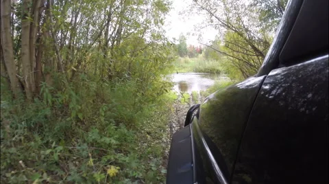 The car down to the river on a slippery road and the river moves. Off-road. Stock Footage 68040408