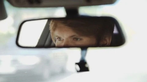 Car driver seen in a rear mirror during a ride Stock Footage 75715181