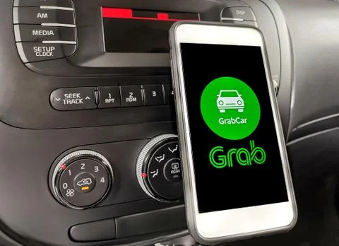 Car driver using smartphone with with Grab app on dashboard. Selective focus 스톡 사진