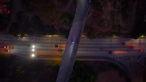 Car drives across overpass at night with busy 5 lane highway below. Headlights Stock Footage 324958524