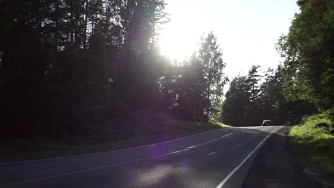 The car drives along an empty road. The sun is shining into the lens. Stock Footage 150108296