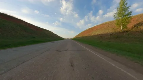 The car drives along the road between two hills covered with green grass. A trip Stock Footage 154524639