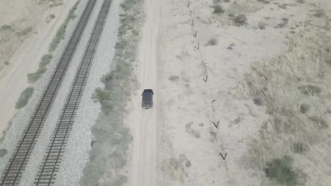 A car drives along side the train tracks in the desert Stock Footage 192586905