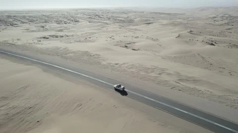 A car drives on asphalt through the Namib Desert Stock Footage 264602653